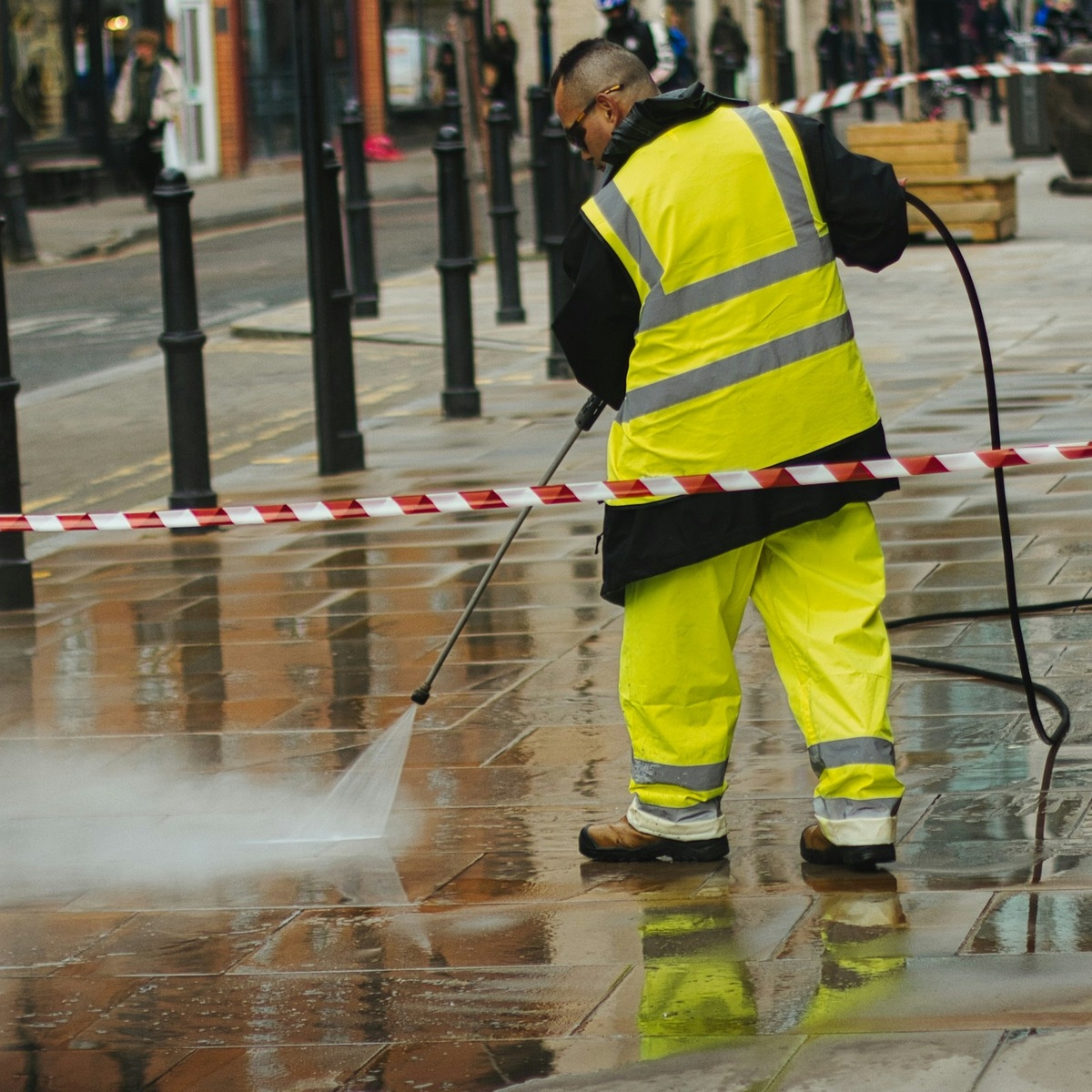Worker wearing high-visibility safety clothing pressure washing a paved sidewalk during pressure washing services in Palmyra, TN